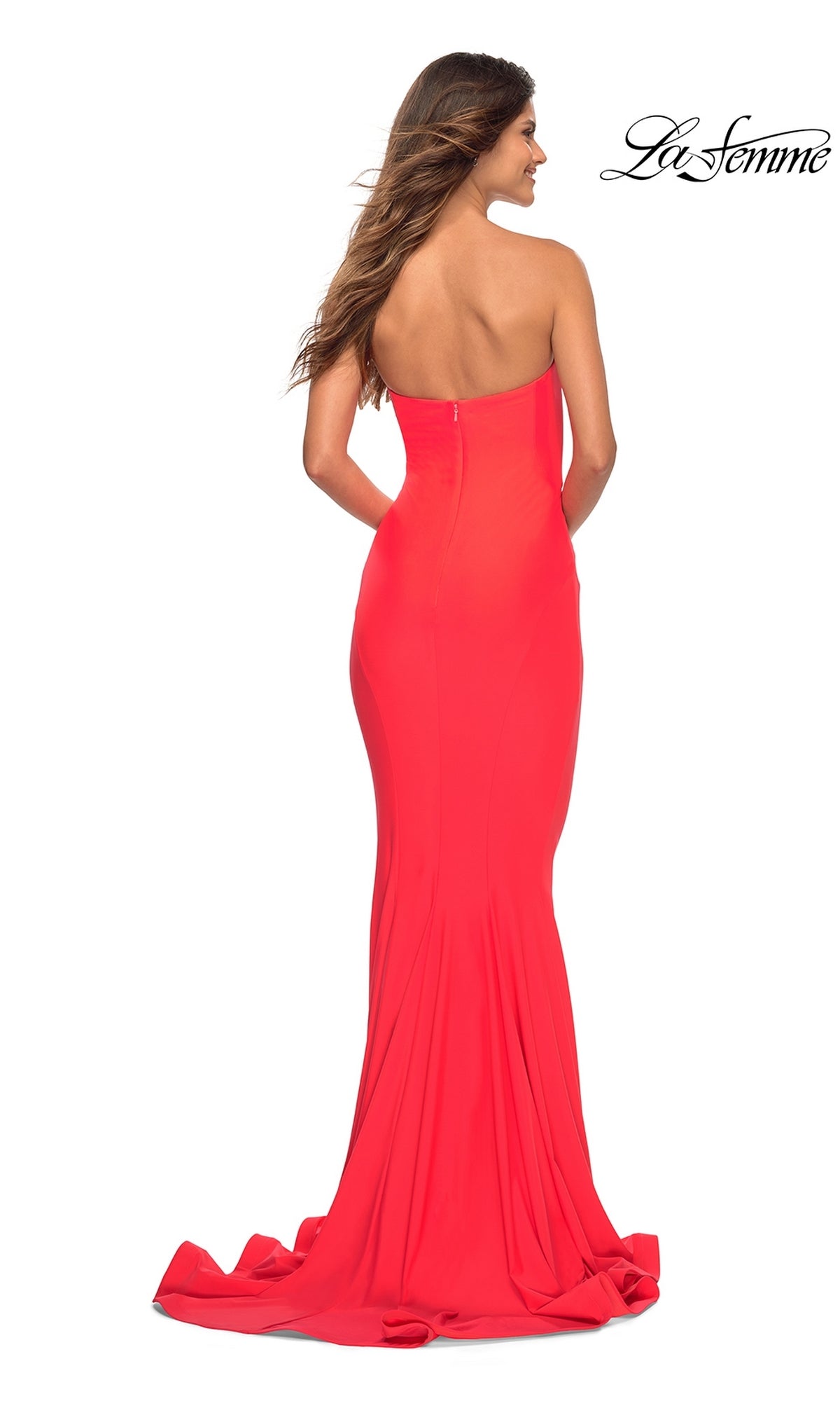 A woman models the La Femme Hot Coral Simple Strapless Prom Dress, a fitted, floor-length gown with a slight train and zipper closure, shown from the back for an elegant designer look.
